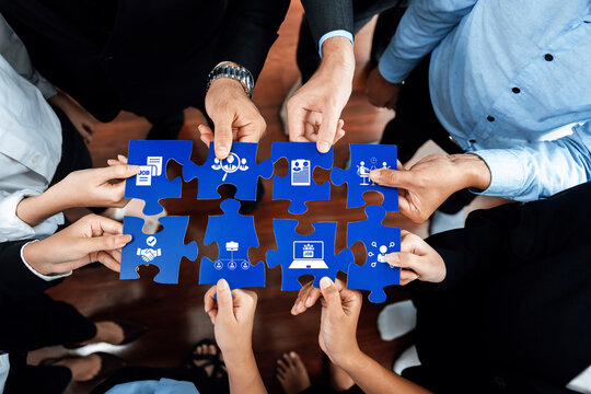 A diverse team gathers around a puzzle, using hands to symbolize collaboration, ideas, and strategies. Icons on pieces represent various concepts related to success in business. Amity
