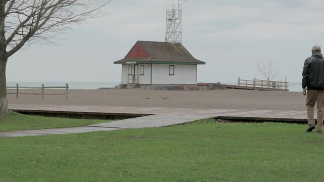 Man walking past historic Leuty Lifeguard Station on rainy overcast day at Kew Beach, Toronto, Ontario, Canada