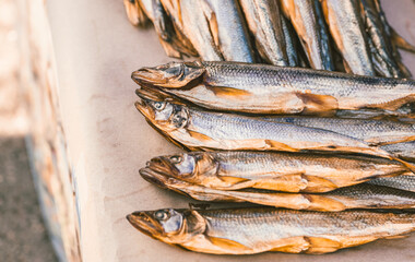 Obraz premium Dried salted fish arranged in row on market stall. Traditional snack seafood product for sale. Healthy protein food concept. Close up view of tasty small dried smelt for consumption.