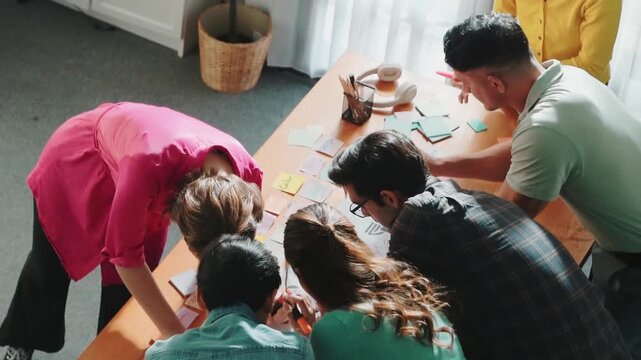 Top view of smart designer team writing comment to develop product. Professional business people working together to design logo graphic while manager explain idea to colleague at meeting. Symposium.