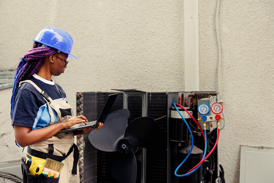 Qualified electrician commissioned to optimize HVAC system efficacy, ensuring it operates at maximum ability. Licensed efficient electrician doing air conditioner survey, imputing data on laptop