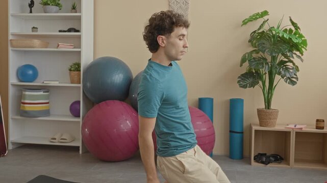 Man on mat kneeling in a supported backbend with hands holding heels in a studio; serenity mindfulness.