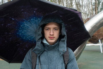Serious teenage boy under galaxy print umbrella in rain © Ruslan Russland
