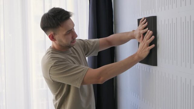 Soundproofing test on acoustic board. Evaluating sound insulation with acoustic panel testing. Technician assesses soundproofing effectiveness of acoustic panels in studio