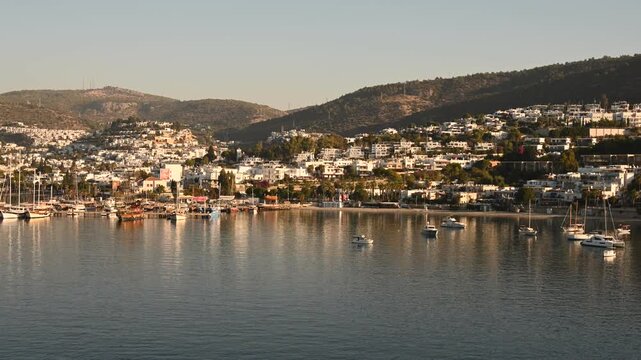 Time-lapse overlooking a tranquil harbor and hillside town on the island of Crete, Greece. Calm Mediterranean waters reflect the waterfront buildings as changing light creates a scenic view of this pi