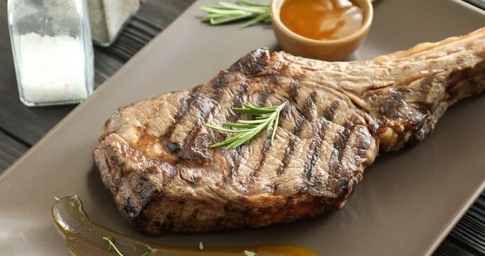 Tasty beef steak served on wooden table, spinning
