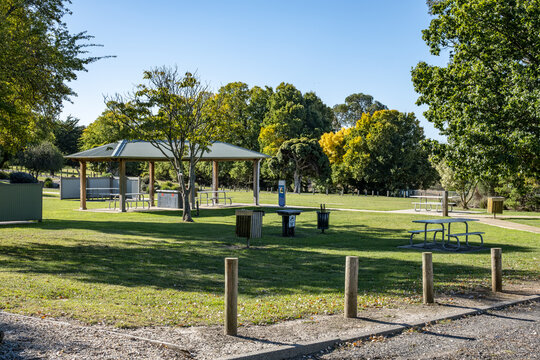 Quiet and well-maintained public park area featuring a picnic shelter, outdoor barbeque, tables, and green lawns in Australia for community recreation. Malmsbury Reservoir Picnic Ground