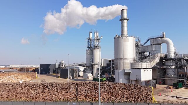 Aerial Biomass Plant With Large Log Stockpile And Plume Of White Steam, Conveyor Systems And Boiler Buildings Visible, Renewable Fuel Supply And Industrial Processing Context