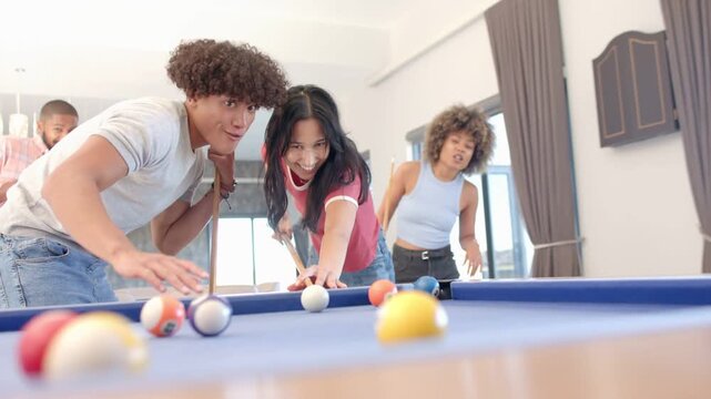 Woman striking cue on blue-felt pool table, friend guiding, animated beams tracing shots for game