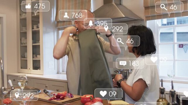 Vertical video: Handing towel, woman helping man don apron as cutting onion at home to cook, icons