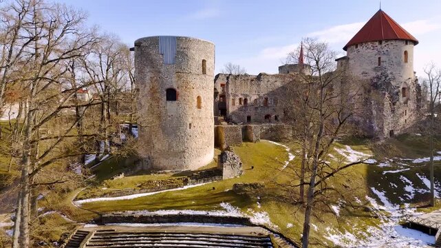 Aerial view of a medieval stone tower above stepped open-air seating and castle ruins, capturing heritage architecture, seasonal park textures, and historic venue atmosphere.