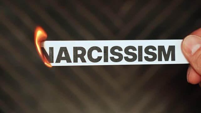 Burning &ldquo;narcissism&rdquo; label held by hand, symbolizing empathy, humility, emotional healing, and freedom from self-centered behavior, manipulation, and toxic relationship patterns.