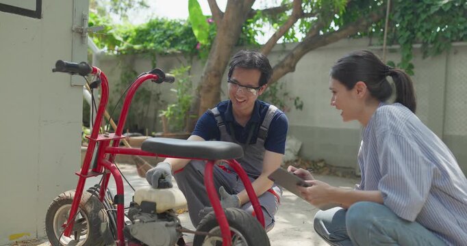 Startup founder and engineer inspect, document and test a minibike prototype outdoors at small business workshop during product development, repair review and SME innovation.
