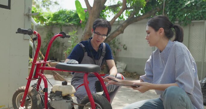 Startup founder and engineer inspect, document and test a minibike prototype outdoors at small business workshop during product development, repair review and SME innovation.
