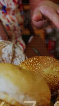 Woman hovering hand over bakery bread, hand entering frame causing flowing charts and binary code