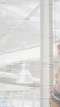 Vertical video: Woman receiving business call while standing by glass wall, atrium beams