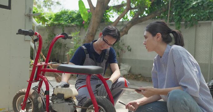 Startup founder and engineer inspect, document and test a minibike prototype outdoors at small business workshop during product development, repair review and SME innovation.
