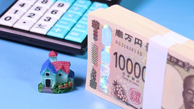 札束とミニチュアハウスと電卓が回転する映像