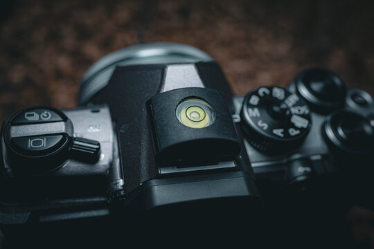 Macro closeup of camera hot shoe bubble level on digital camera top plate with control dial and buttons in low light detail