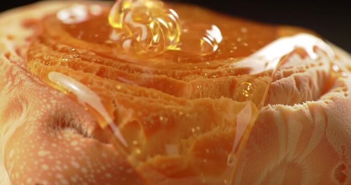 Golden honey dripping over fresh cinnamon roll in close-up macro shot