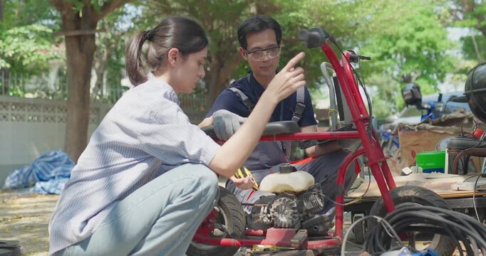 Startup founder and engineer inspect, document and test a minibike prototype outdoors at small business workshop during product development, repair review and SME innovation.
