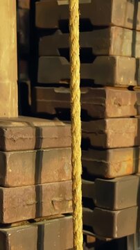 Vertical close-up of theatre counterweight stack and rope backstage, showing fly system mechanics, stage rigging detail, and technical theater infrastructure in warm light.