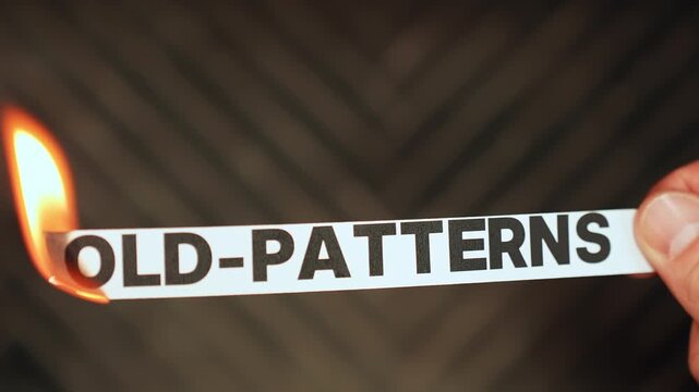 Burning &ldquo;old-patterns&rdquo; label held by hand, symbolizing personal growth, healthier habits, mindset renewal, and leaving repeated self-sabotage behind.