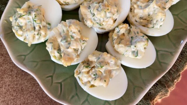 Close-up of creamy deviled eggs on a serving platter, highlighting herb-filled topping and smooth whites in a homemade appetizer presentation.