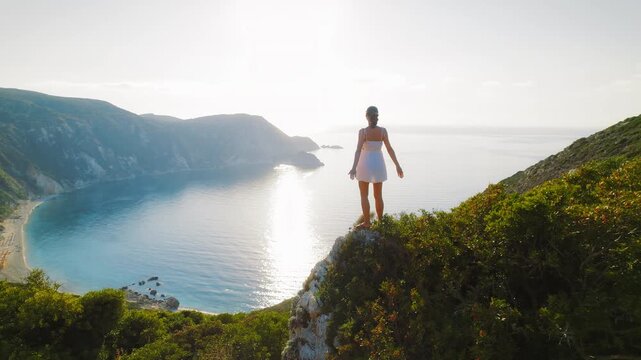 Woman overlooking serene coastal bay in Kefalonia Island Greece at golden hour