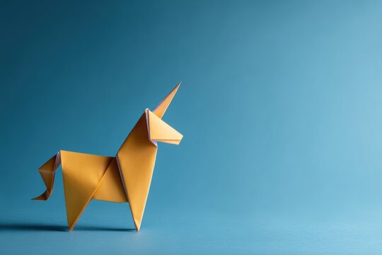 Yellow paper unicorn origami figure on blue background