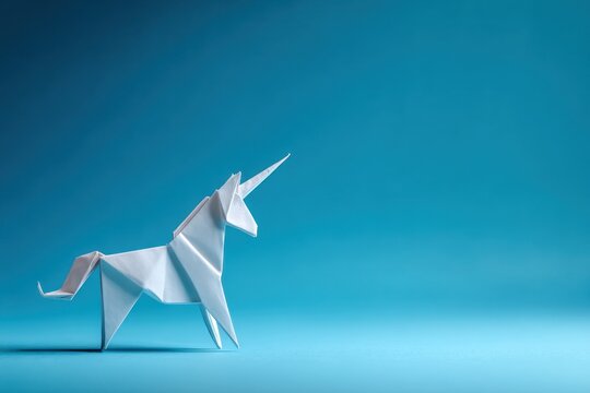 White paper unicorn origami figure against a solid blue background.