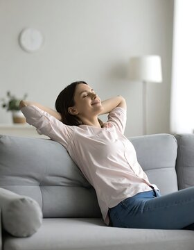 A woman relaxing on a couch with her hands behind her head