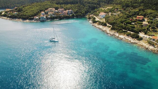 Aerial view of sailboat floating near Fiskardo village houses on Kefalonia coast