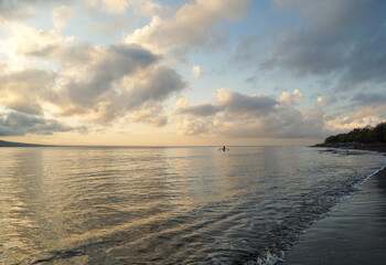 Obraz premium Small fishing boat sailing on the calm Bali Strait during golden sunrise, Banyuwangi. 