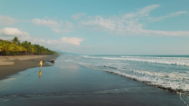 Woman walking at Linda beach coastline with waves and sandy shore in Costa Rica