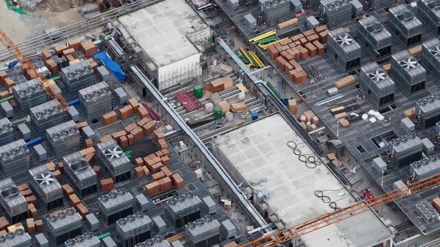 Close aerial drone view of rooftop cooling systems on a hyperscale data center under construction, showing thermal infrastructure, industrial engineering, and digital facility development.
