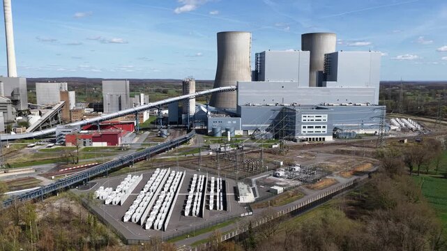 Aerial drone video of a decommissioned power station complex with large cooling towers and a battery storage park under construction, showing energy transition, grid stabilization.