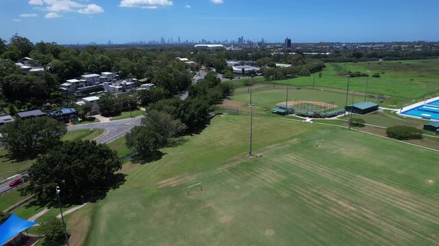 Aerial View Of Firth Park In Mudgeeraba, QLD, Australia - Green Playing Field With Gold Coast Skyline In Distance.