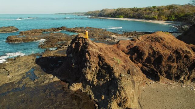 Traveler stands on a rocky cliff overlooking San Juanillo beach in Costa Rica