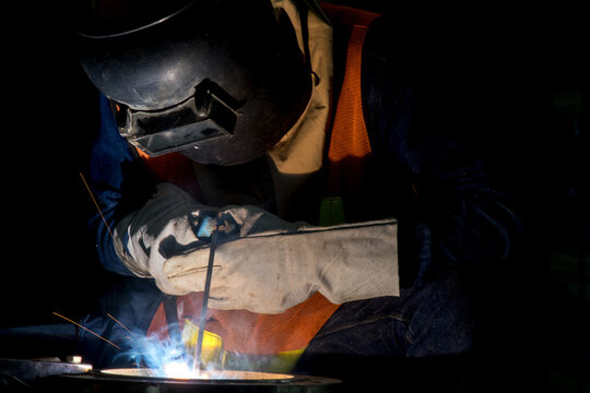Industrial welder welding fabricated construction in factory Welding process by Shielded Metal Arc Welding (SMAW) or Stick Welding.