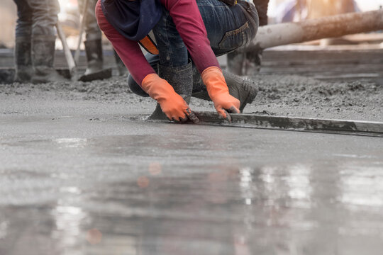 Construction worker troweling wet concrete on a top of concrete floor slab new construction site