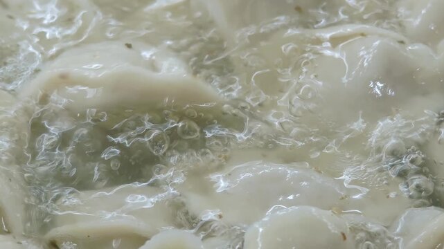 Boiling dumplings in a pot with bubbling water, showcasing the cooking process and texture of the dumplings as they float and move in the hot liquid