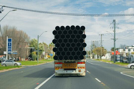 Oversize truck carrying large diameter poly pipes on a suburban road