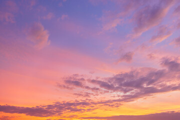 Naklejka premium Beautiful sunset sky with golden light and purple clouds over the horizon,Dramatic sunset sky background with soft orange sunlight and scattered dark clouds during twilight. The evening atmosphere.