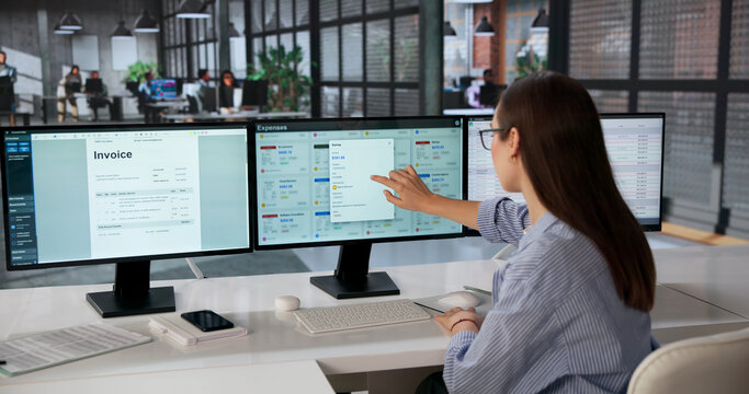 Young Woman Analyzes Financial Data Across Multiple Computer Screens