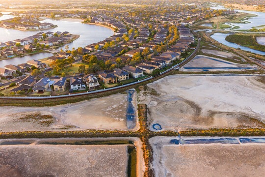 Aerial view of coastal salt ponds and levee banks near the edge of suburban housing