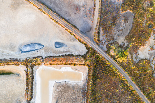 Aerial view of levee banks and colourful evaporation ponds at a coastal salt works