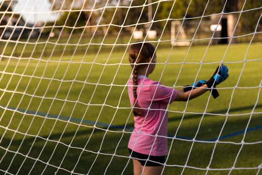 girl putting on goalkeeper gloves at a soccer field
