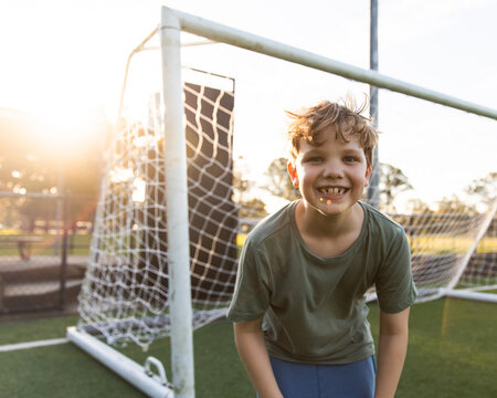 kid with a cheeky grin in front of a soccer goal