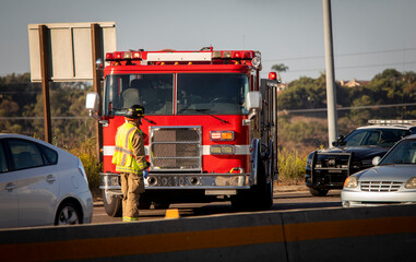 Fototapeta premium Firefighters and a fire truck at an accident scene on a freeway